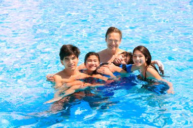 Multiracial family swimming together in pool. Disabled youngest  clipart