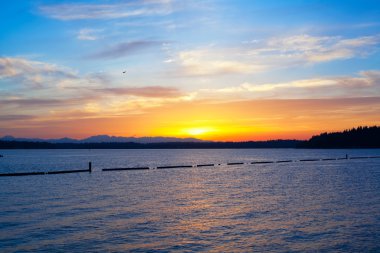 Yellow orange sunset with blue sky over blue waters of lake