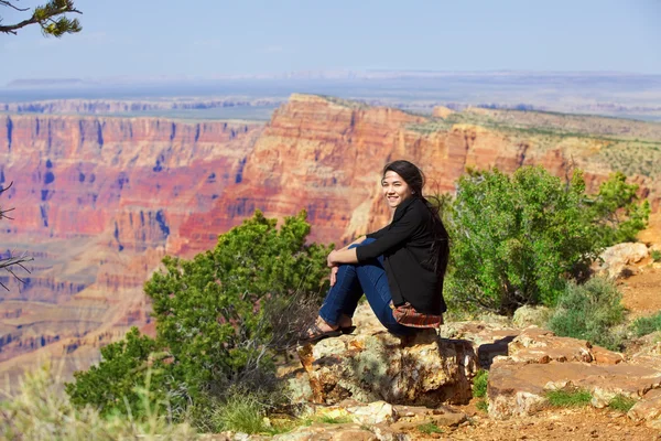 Biracial teen girl sitting along rock ledge at Grand Canyon — Stock Photo, Image