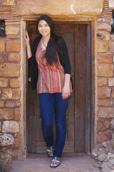Biracial teen girl standing in brick doorway of home — Stockfoto