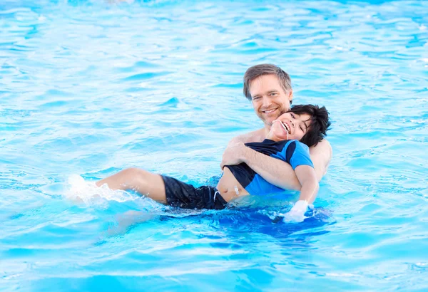 Père nageant dans la piscine avec enfant handicapé — Photo