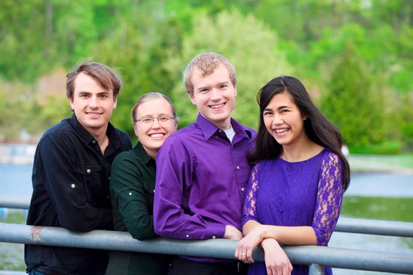 Four young multiethnic friends together outdoors by lake — Stok fotoğraf