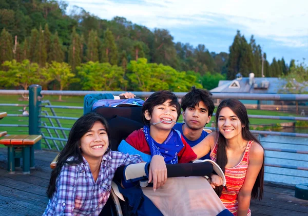 Brother and sisters outdoors,  hanging out at park with disabled — Stockfoto