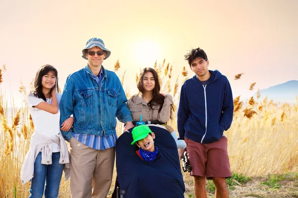 Caucasian father standing by field of tall grasses with biracial — Stock Photo, Image