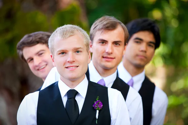 Groomsmen peeking da dietro sposo, all'aperto — Foto Stock