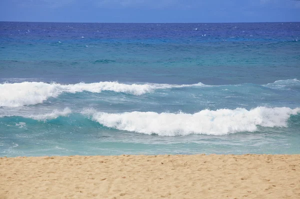 Blue waters and waves on a Hawaiian beach on sunny day Stock Image