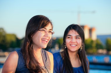 Gülümseyen ve açık havada konuşurken iki biracial genç kadın