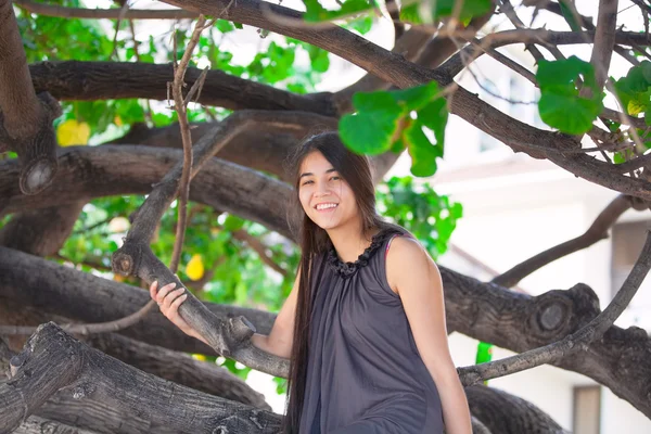 Biracial teen dziewczyna siedzi na gałęzi drzewa na plaży — Zdjęcie stockowe