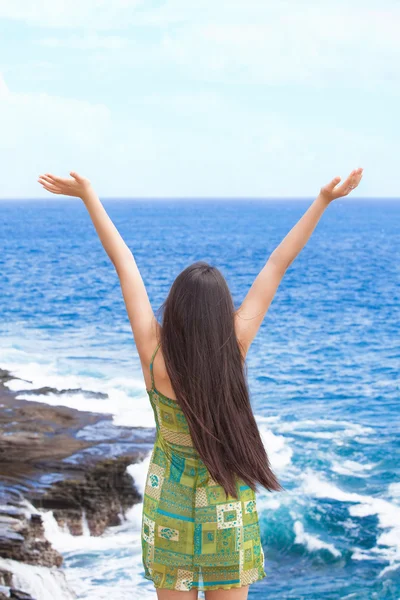 Teen girl arms raised by ocean water in praise — Stockfoto