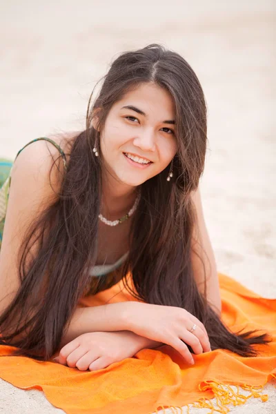 Biracial yeen girl lying on orange blanket at beach — Stock Photo, Image