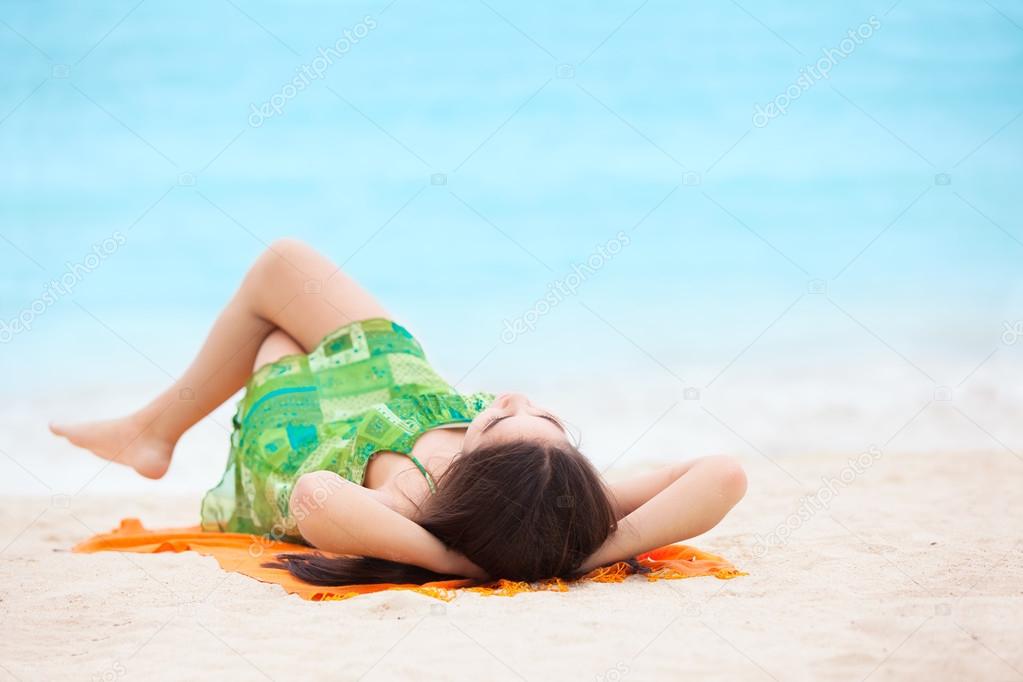 Biracial teen girl arms lying on beach relaxing by ocean water