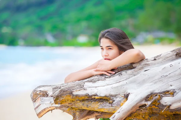 Mooie tiener meisje op het strand bidden door drijfhout log — Stockfoto