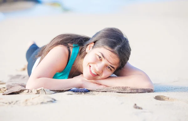 Береговая девушка-подросток лежит на песчаном пляже, отдыхает и улыбается — стоковое фото