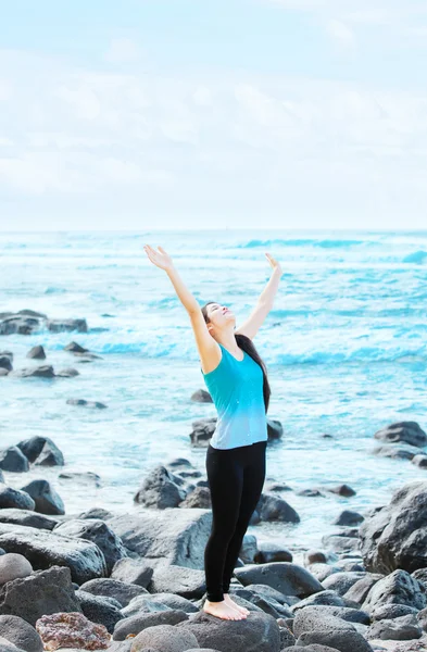 Biracial teen girl on rocks by ocean praising God — Stock Photo, Image