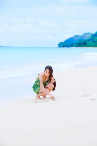 Krásná dospívající dívka výkres srdce v písku na tropické pláži — Stock fotografie