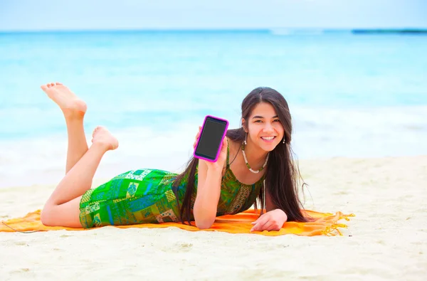 Krásná biracial dospívající dívka leží na tropické pláži s telefonem — Stock fotografie
