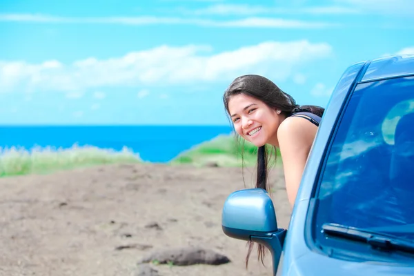 Senyum gadis remaja birasial bersandar di luar pintu mobil oleh laut — Stok Foto