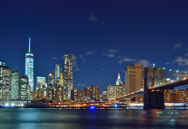 Manhattan skyline with Brooklyn Bridge at night.