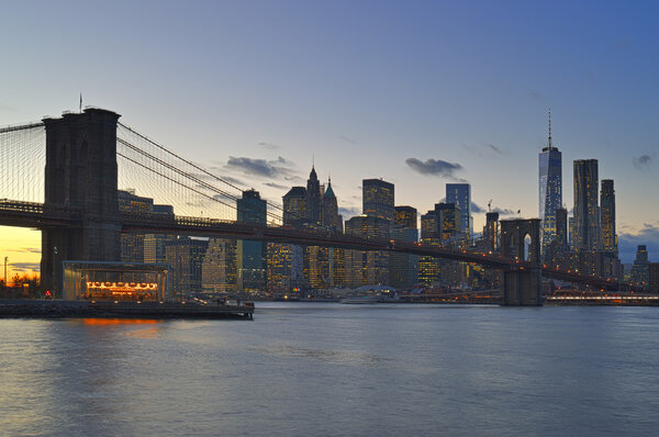 Manhattan skyline with Brooklyn Bridge at twilight.