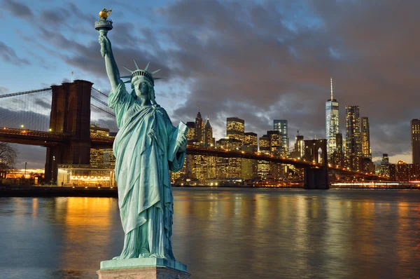 Manhattah skyline bij nacht en Statue of Liberty. — Stockfoto