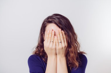 Kadın elini yüzünü kapatıyor.