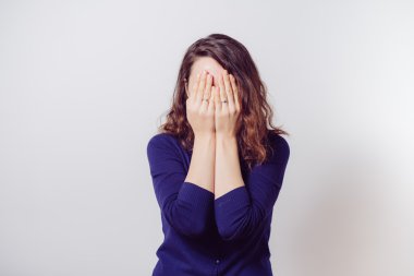 Kadın elini yüzünü kapatıyor.