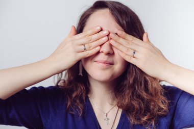 Kadın elini yüzünü kapatıyor.