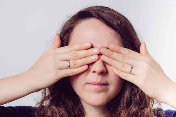 Žena zavírá oči svýma rukama — Stock fotografie