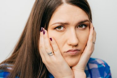 kız ellerini yanaklarda tutar.