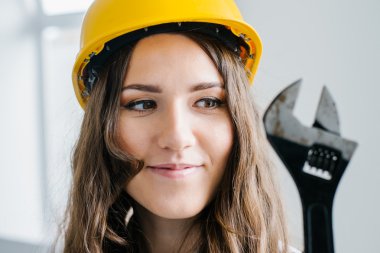 Kız bir İngiliz anahtarı tutan bir kask içinde