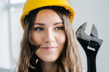 Kız bir İngiliz anahtarı tutan bir kask içinde