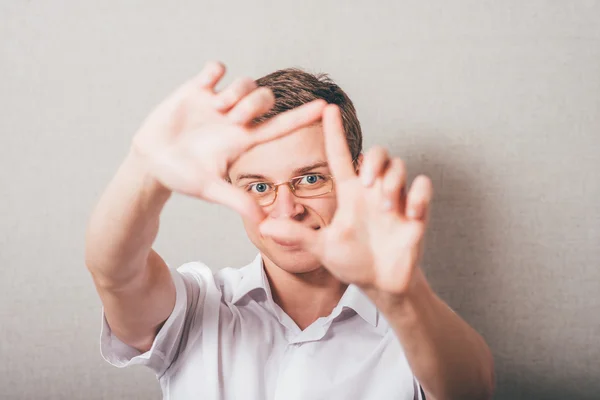 Man op zoek via frame van vingers — Stockfoto