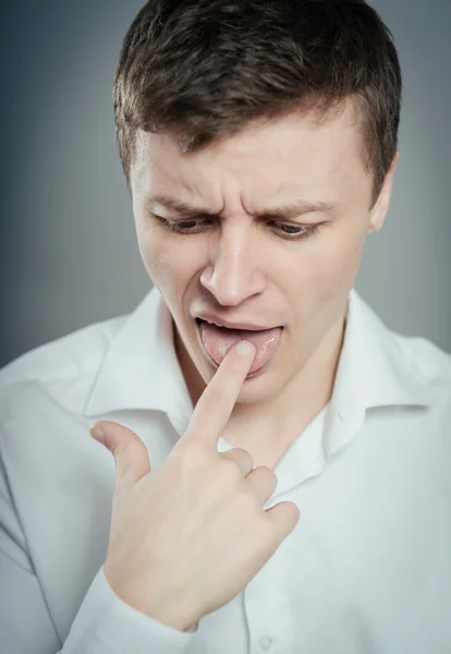 Man puts finger in mouth — Stock Photo, Image