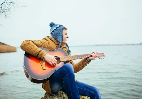 Man playing on guitar at the lake — Stock Photo, Image
