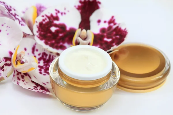 Creme facial e corporal com orquídea sobre fundo branco — Fotografia de Stock