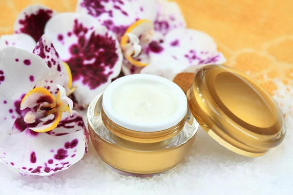 Creme facial e corporal com orquídea, sal marinho na frente — Fotografia de Stock