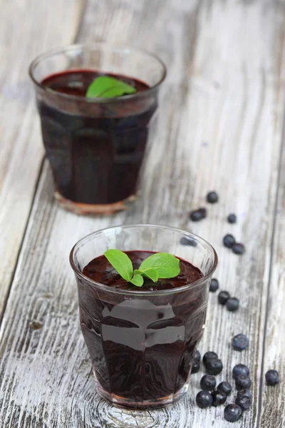 Frischer Blaubeer-Smoothie im Glas und Blaubeeren herum — Stockfoto