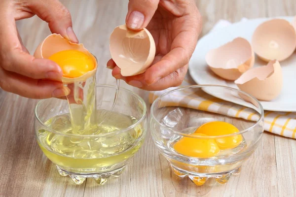 Vrouw handen breken een ei-eiwit en dooier scheiden — Stockfoto