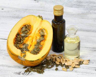 Balkabağı tohumlarından yapılan yağ. Yağ kabağı ikiye bölünmüş, etrafta taze kabak tohumları var..