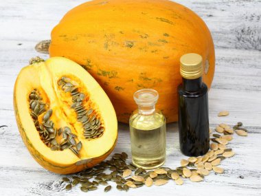Balkabağı tohumlarından yapılan yağ. Yağ kabağı ikiye bölünmüş, etrafta taze kabak tohumları var..