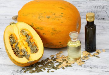Balkabağı tohumlarından yapılan yağ. Yağ kabağı ikiye bölünmüş, etrafta taze kabak tohumları var..