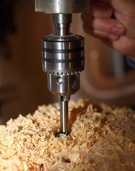 Milling cutter with sawdust in action. Closeup of milling machine making holes in the wood