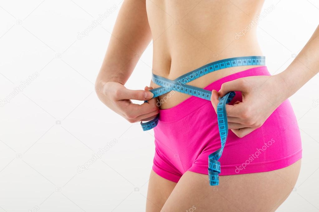 Fitness girl measuring her perfect shapeed beautiful waist.