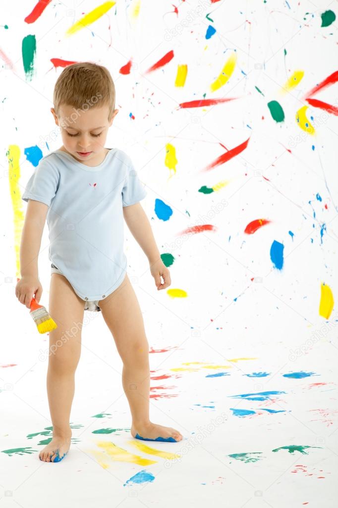 Adorable 3 year old boy child creatively stains on the wall.