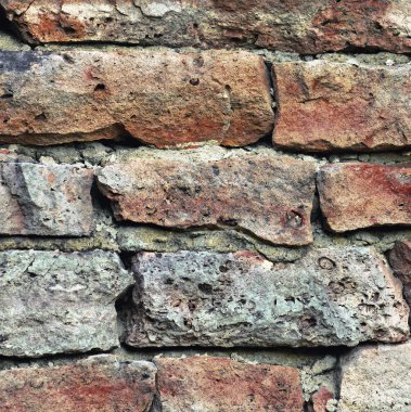 Stone wall macro closeup, stonewall pattern background, old aged weathered red and grey grunge limestone dolomite calcium carbonate hard sedimentary slate slab rock texture, natural grungy textured bricks, beige, yellow, reddish, gray brick vintage