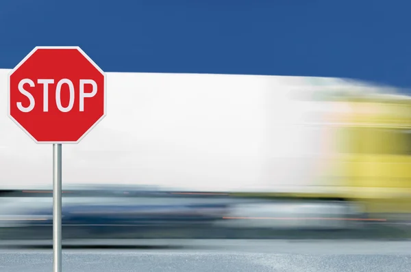 Red stop road sign, motion blurred truck vehicle traffic in background, regulatory warning signage octagon, white octagonal frame, metallic pole post — Stock Photo, Image