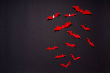 Cadılar Bayramı kompozisyonu. Siyah arka planda kırmızı yarasa sürüsü. Cadılar bayramın kutlu olsun, şeker mi şaka mı partisi konsepti. Düz konum, üst görünüm, kopyalama alanı.