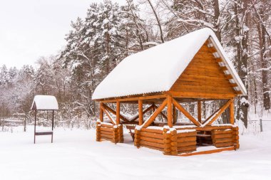 Kışın karla kaplı kır köyünde rahatlamak için bir yer. Kar yağdıktan sonraki kış, bulutlu bir havada ahşap çardak ve mangal. Sezon detayları, soğuk hava