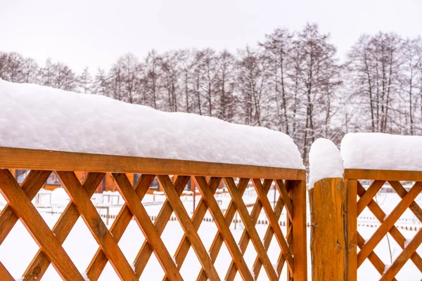 Wooden fence covered with snow in winter cloudy day after snowfall. Winter season, cold weather concept. Beautiful winter background in rustic style, copy space.