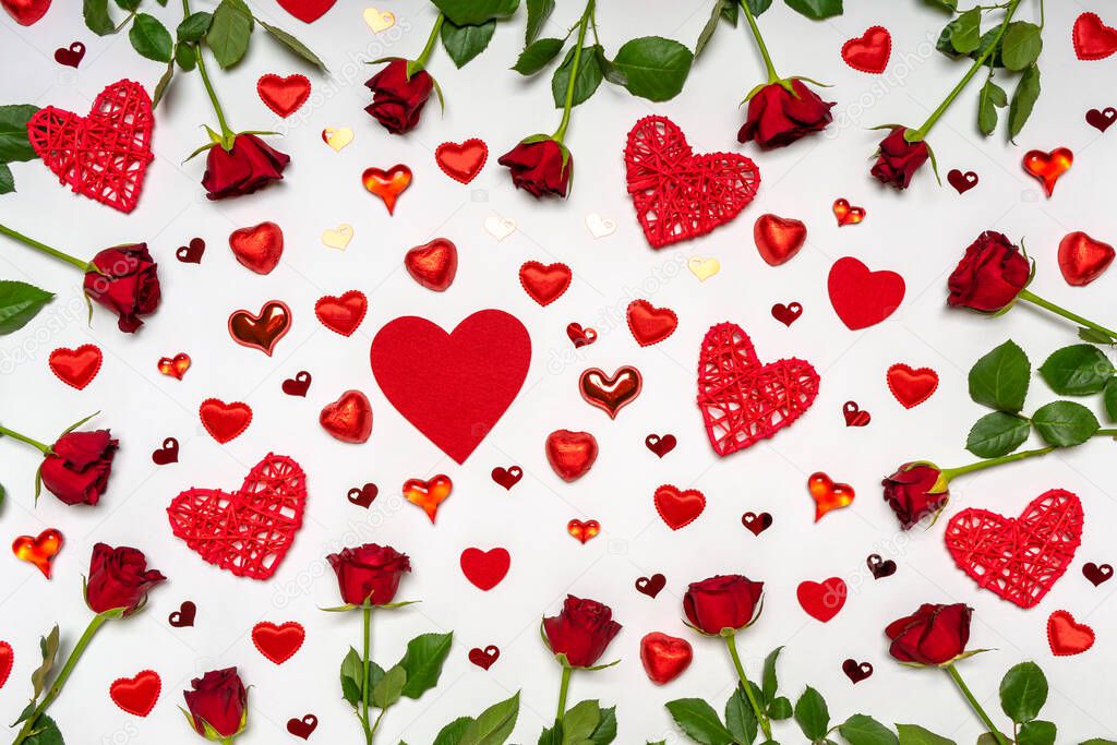 Creative composition made of fresh red roses flowers, hearts and sweets on white background. Beautiful arrangement, greeting card. Love, romance or Valentine's day concept. Flat lay, top view.